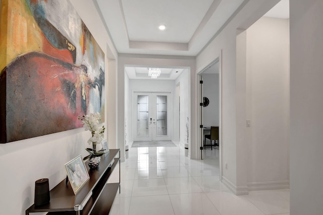 hallway featuring french doors, a tray ceiling, and light tile patterned floors