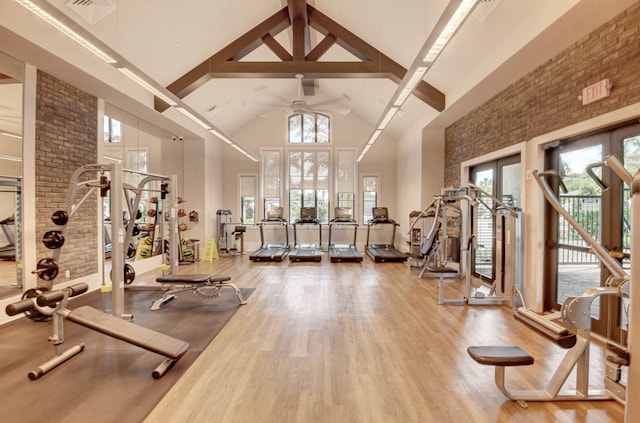 workout area featuring brick wall, high vaulted ceiling, ceiling fan, and wood-type flooring