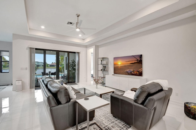 tiled living room with a raised ceiling, french doors, ceiling fan, and plenty of natural light