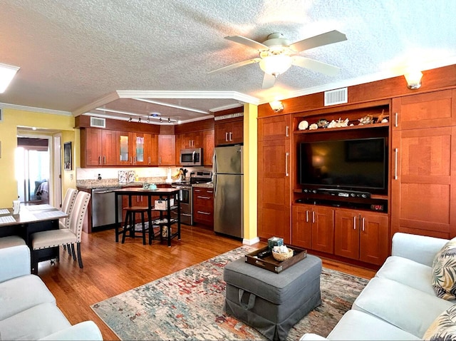 living room featuring a textured ceiling, ceiling fan, ornamental molding, and hardwood / wood-style floors