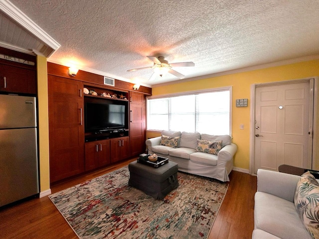 living room with dark wood-type flooring, a textured ceiling, ceiling fan, and ornamental molding