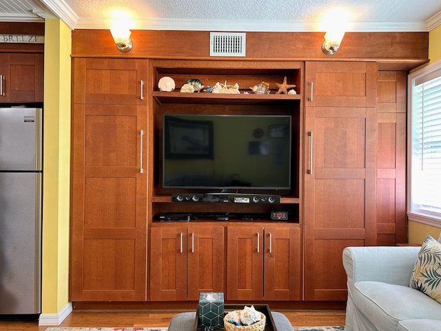 living room featuring ornamental molding, a healthy amount of sunlight, and light hardwood / wood-style flooring