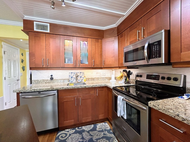 kitchen featuring light stone countertops, hardwood / wood-style flooring, crown molding, appliances with stainless steel finishes, and sink