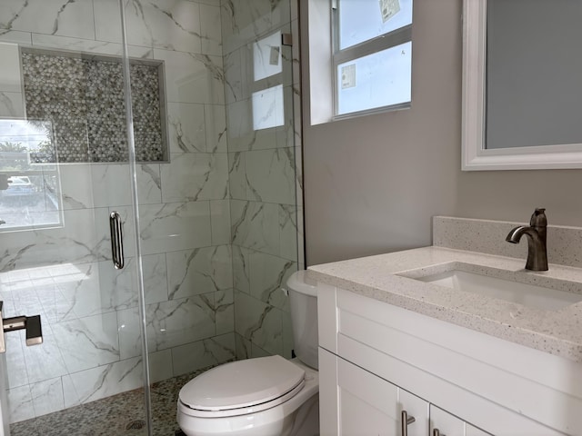 bathroom featuring toilet, a shower with door, and vanity