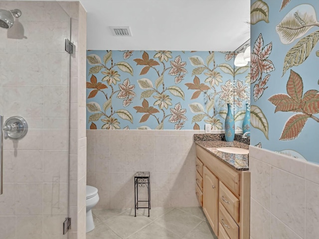 bathroom featuring tile patterned floors, toilet, tile walls, and an enclosed shower