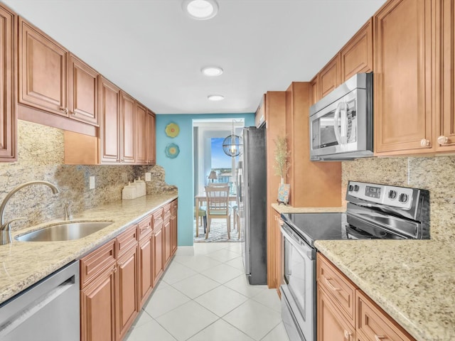 kitchen with light stone countertops, sink, backsplash, light tile patterned floors, and appliances with stainless steel finishes