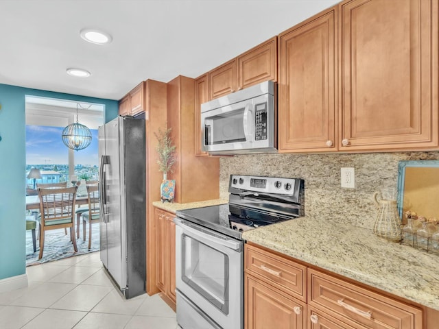 kitchen featuring pendant lighting, backsplash, appliances with stainless steel finishes, a notable chandelier, and light tile patterned flooring