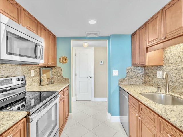 kitchen with backsplash, sink, light stone countertops, and stainless steel appliances