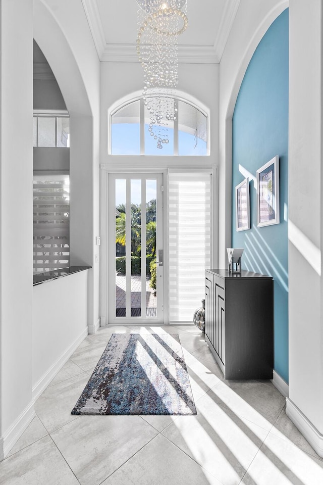 entrance foyer with ornamental molding, french doors, a high ceiling, and an inviting chandelier