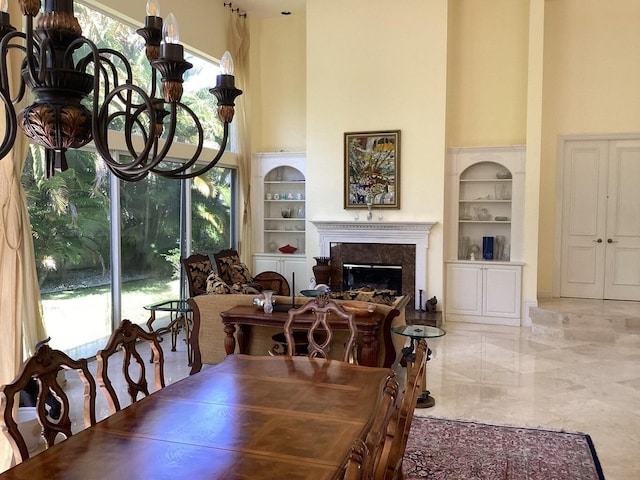 dining room featuring a fireplace, built in features, and a high ceiling