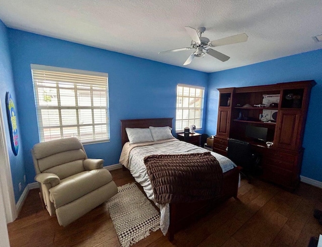 bedroom featuring ceiling fan, dark hardwood / wood-style flooring, and a textured ceiling