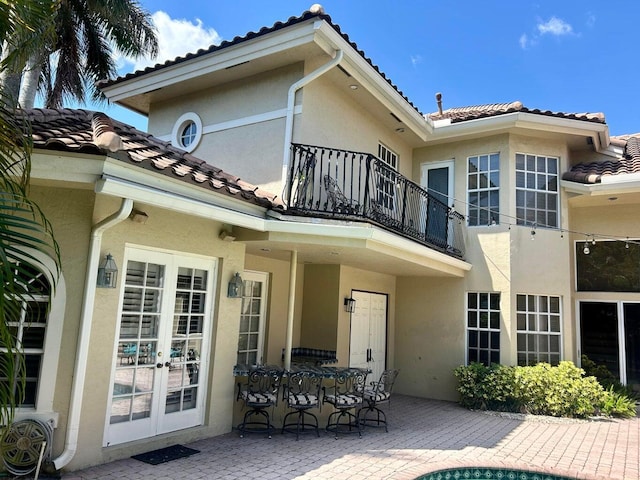 rear view of house featuring a patio area, a balcony, and french doors