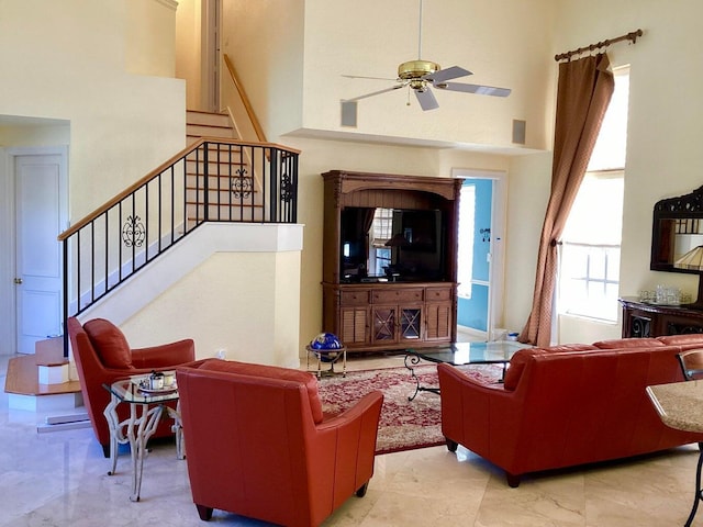 living room with ceiling fan and a towering ceiling