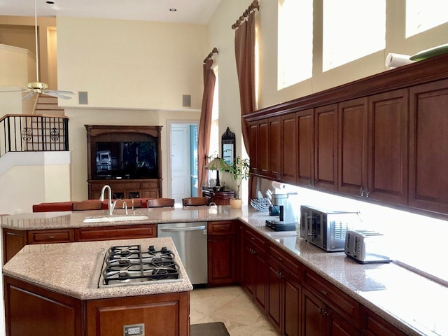 kitchen with sink, light stone countertops, light tile patterned floors, appliances with stainless steel finishes, and kitchen peninsula