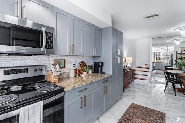 kitchen featuring stone counters, appliances with stainless steel finishes, decorative backsplash, and gray cabinets