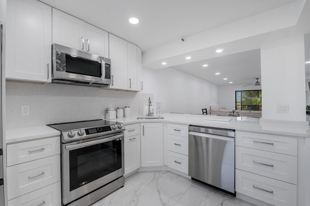 kitchen featuring appliances with stainless steel finishes, kitchen peninsula, sink, and white cabinets