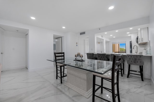 kitchen with white cabinetry, a kitchen bar, kitchen peninsula, and sink