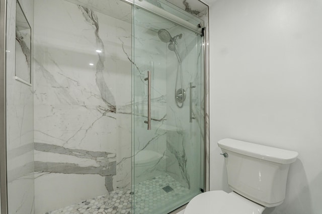 bathroom featuring a shower with shower door and toilet