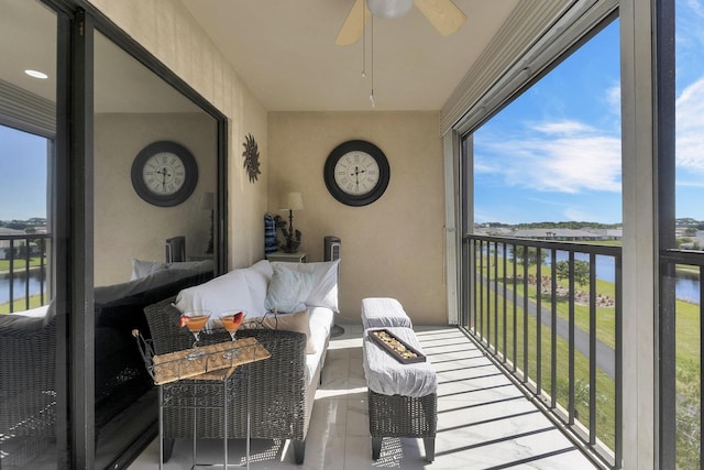 sunroom / solarium featuring ceiling fan and a water view