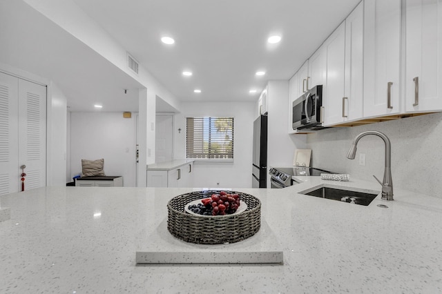 kitchen featuring stainless steel appliances, light stone countertops, sink, and white cabinets