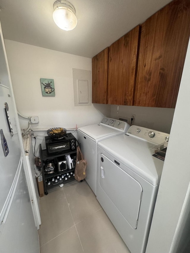 clothes washing area featuring cabinets, light tile patterned floors, electric panel, and washer and clothes dryer