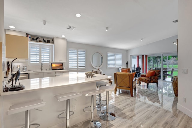 kitchen with a kitchen bar, light hardwood / wood-style floors, sink, and white cabinets