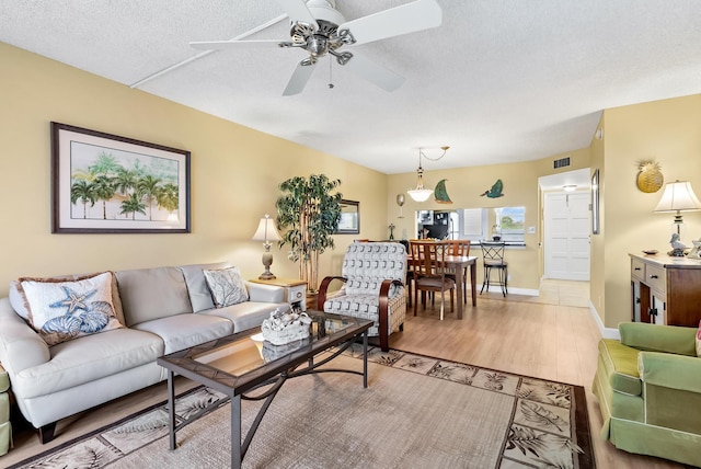 living room featuring a textured ceiling, ceiling fan, and light hardwood / wood-style flooring