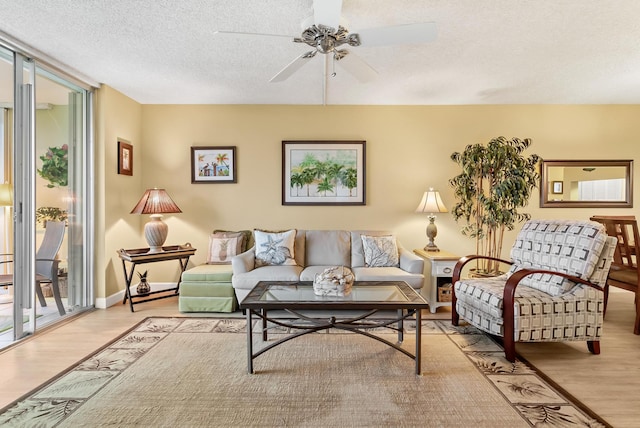 living room featuring ceiling fan, light hardwood / wood-style floors, a textured ceiling, and expansive windows