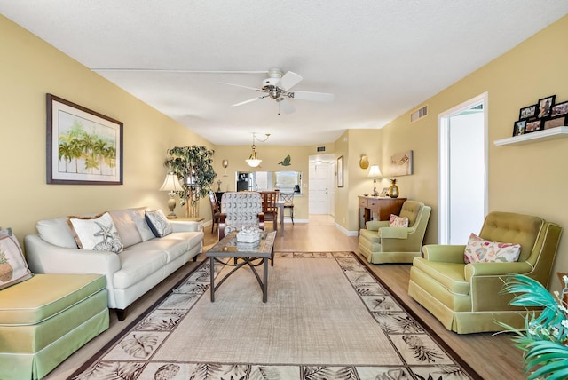 living room featuring ceiling fan, a textured ceiling, and hardwood / wood-style flooring