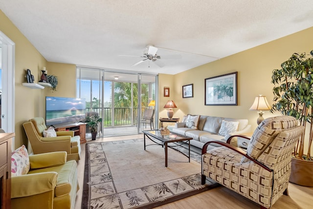 living room with ceiling fan, expansive windows, a textured ceiling, and light hardwood / wood-style floors