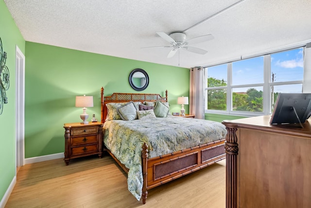 bedroom featuring ceiling fan, a textured ceiling, and light wood-type flooring