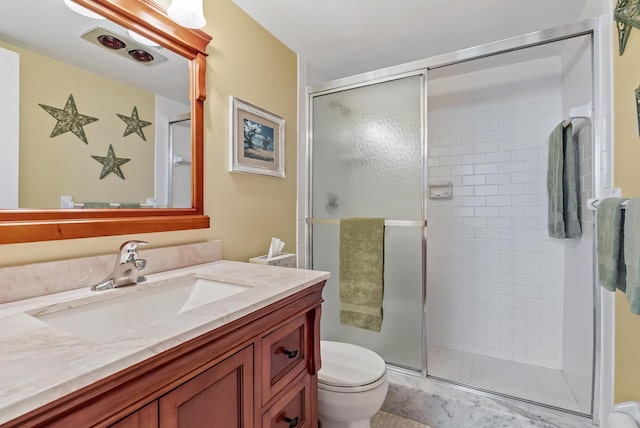 bathroom featuring toilet, vanity, and a shower with door