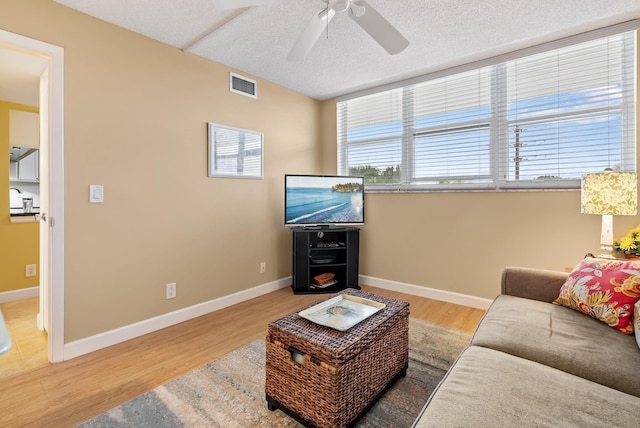 living room with ceiling fan, a textured ceiling, and hardwood / wood-style floors