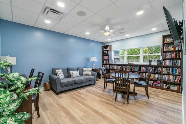 interior space with ceiling fan, a drop ceiling, and light hardwood / wood-style flooring