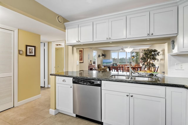 kitchen featuring stainless steel dishwasher, white cabinets, dark stone counters, and sink