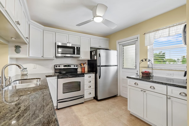 kitchen with appliances with stainless steel finishes, backsplash, dark stone counters, white cabinets, and sink