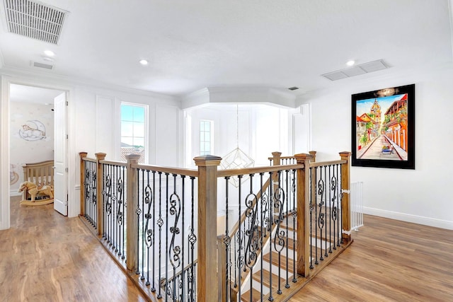 hall with ornamental molding, light hardwood / wood-style floors, and a notable chandelier