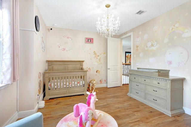 bedroom with a chandelier, light hardwood / wood-style flooring, and a crib