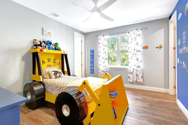 bedroom featuring ceiling fan, hardwood / wood-style floors, and a textured ceiling