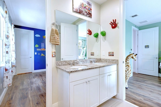 kitchen featuring white cabinetry, sink, light stone counters, and light hardwood / wood-style flooring