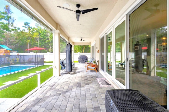 unfurnished sunroom featuring ceiling fan