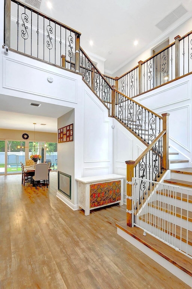 staircase with ornamental molding and hardwood / wood-style floors