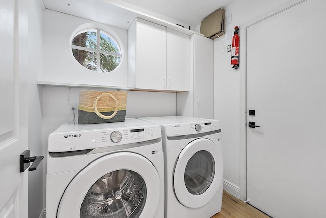 washroom with cabinets, washing machine and dryer, and light wood-type flooring