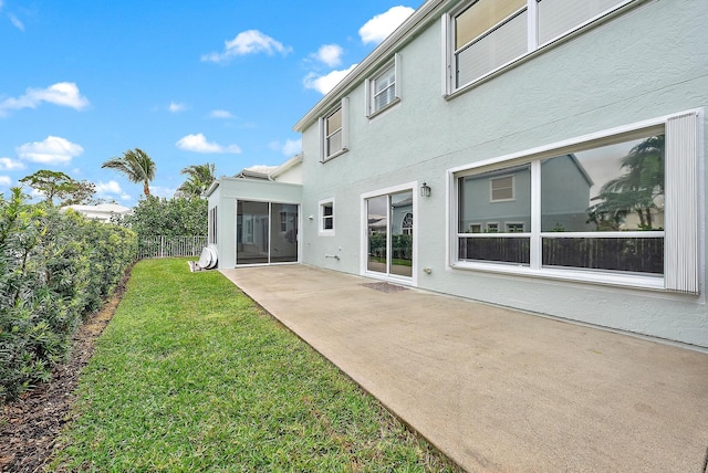 rear view of property with a lawn, a sunroom, and a patio