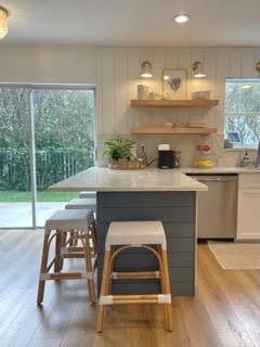 kitchen featuring light hardwood / wood-style floors, a breakfast bar, white cabinetry, and stainless steel dishwasher