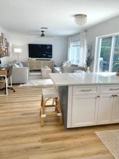 kitchen with light hardwood / wood-style floors, white cabinetry, and a breakfast bar area