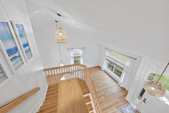 stairs with high vaulted ceiling and hardwood / wood-style floors