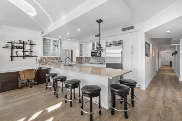 kitchen with stainless steel appliances, beverage cooler, backsplash, white cabinetry, and wood-type flooring