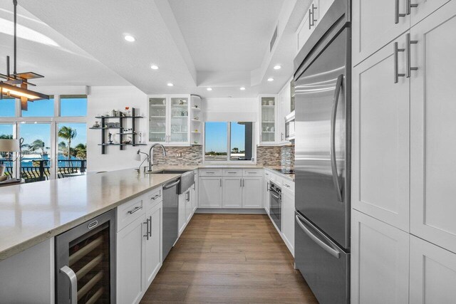 kitchen with appliances with stainless steel finishes, light hardwood / wood-style floors, decorative backsplash, and white cabinetry