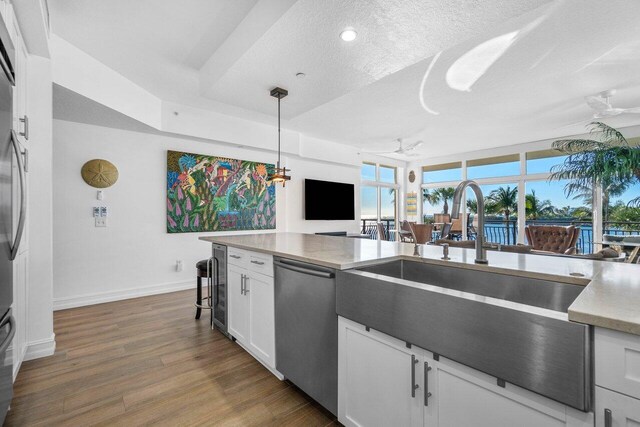 kitchen featuring a kitchen breakfast bar, beverage cooler, pendant lighting, white cabinetry, and tasteful backsplash